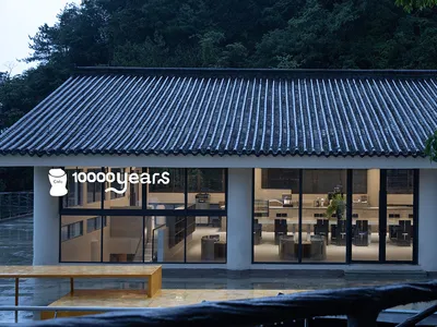 A minimalist restaurant with concrete walls and large windows, featuring modern furniture and a clean design.