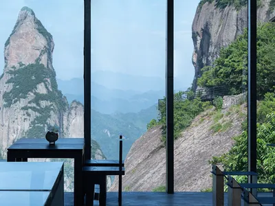 A modern restaurant interior with glass walls overlooking a scenic mountain view.