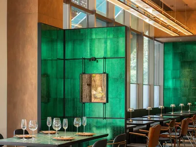 Modern restaurant interior with a prominent green-tile backdrop.