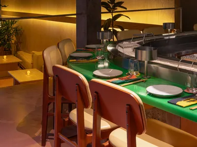 A modern restaurant interior design featuring composite materials, including green countertops and stainless steel elements.