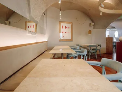 A modern restaurant interior with concrete walls and tables.