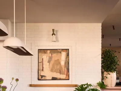 Modern dining room with wooden tables, concrete floor, brick wall, and leather chairs.