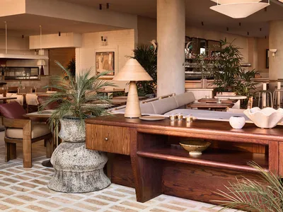 A spacious Mediterranean restaurant with wood furnishings, concrete accents, and cement flooring.
