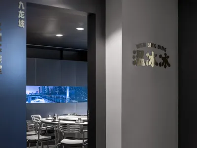 Modern restaurant with sleek design, glass cabinets, and silver chairs.