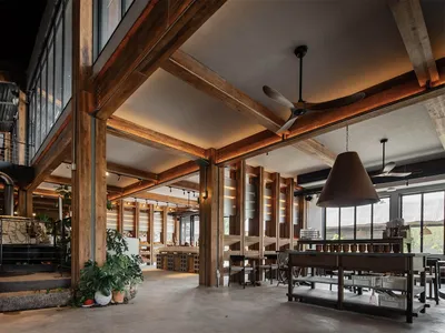 Industrial-style restaurant interior with wooden beams, concrete flooring, and metal accents.