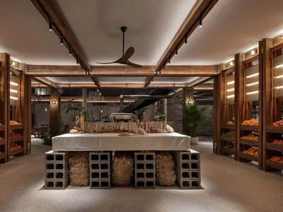 Industrial-style restaurant interior with wooden structures, concrete elements, and hay accents.