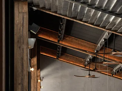 Industrial-style restaurant interior with wooden beams, concrete walls, and ceiling fans