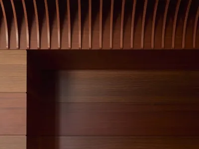 A modern restaurant booth made of wood with a sleek design, featuring plush seating and a small table with glasses and cutler