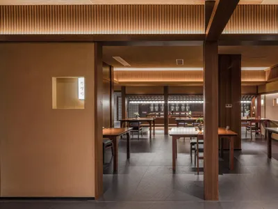 Modern restaurant interior with wooden tables, rustic wooden walls, and warm lighting.