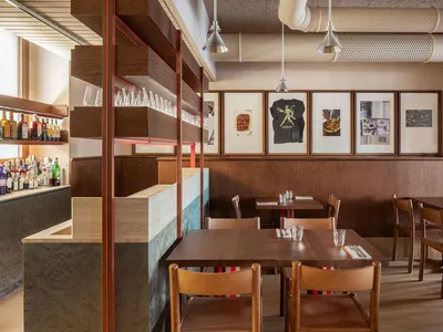 A cozy, industrial-themed restaurant interior with wooden tables, chairs, and shelves.