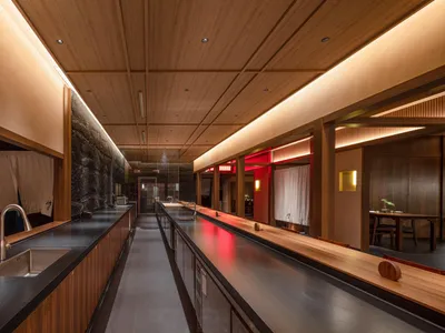 A modern restaurant bar with wooden surfaces, sinks, and lighting.
