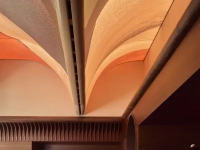 Modern restaurant interior with plush seating, metallic accents, and acoustic panels.