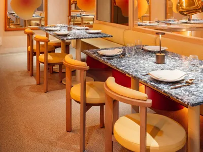 Modern restaurant interior with marble tables, leather seating, and wood accents.