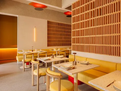 Modern restaurant interior featuring yellow seating, wooden accents, and concrete flooring