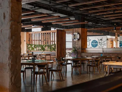 Industrially styled restaurant interior with wooden tables, chairs, and stone pillars