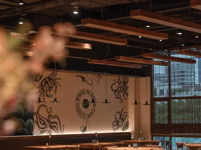 Interior design of a modern restaurant featuring wooden furniture and wall murals with marine-themed illustrations.