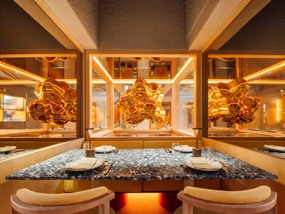 A contemporary restaurant interior designed with marble tables and wooden seating.