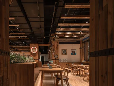 Interior of a restaurant with industrial design elements made of wood, including wooden tables, chairs, and ceiling beams.