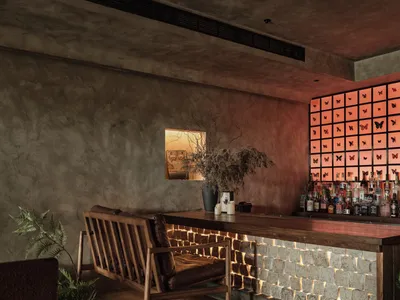 A modern bar interior with concrete walls, brick walls, and wooden furniture.