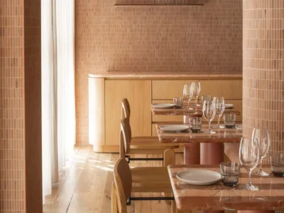 Restaurant interior featuring wooden tables, stone walls, and industrial-style decor.