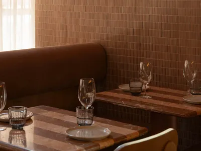 Interior design of a restaurant featuring brown tiles on the walls and wooden tables.