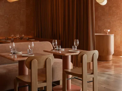 Modern restaurant interior with wooden tables, cork floors, and marble accents