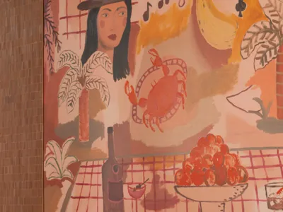 A modern restaurant interior with a table set for a meal, featuring a painting of a woman on the wall and various food items