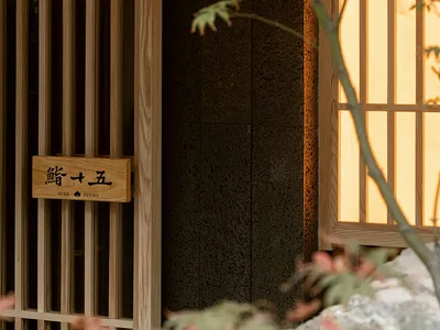 A minimalist restaurant entrance featuring wooden sliding doors and a rock garden.
