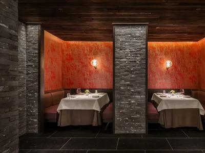 Industrial-themed restaurant with brick and concrete boundary walls, featuring table settings and ambient lighting.