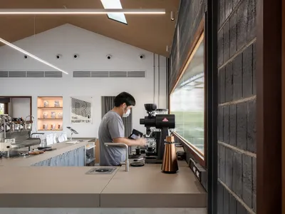 A coffee shop featuring a concrete counter with a barista preparing coffee.