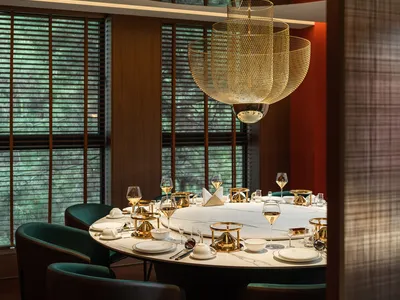 A modern restaurant interior with a round table, brass accents, and marble finishes.