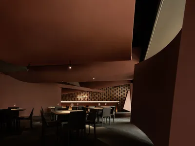 現代餐廳室內，採極簡設計，搭配木質餐桌、磚牆與金屬點綴。