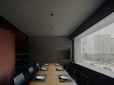 Modern restaurant dining room with black interiors, wooden tables, and white plates on placemats.