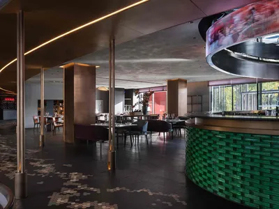 Contemporary restaurant bar interior with metallic columns, concrete walls, and brick seating.