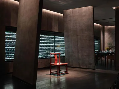 A minimalist restaurant bar with metal furniture and glass walls.