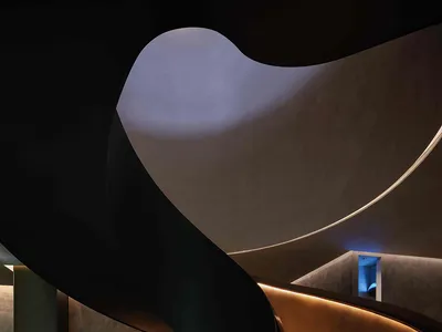 A modern restaurant interior with a spiral staircase featuring metallic and glass materials.