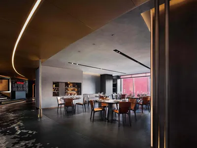 A modern restaurant interior featuring sleek metal, glass, and wooden elements.