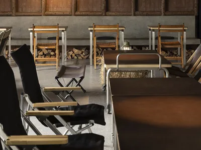 Large, cozy cafe interior featuring wooden tables, concrete walls, metal accents, and fabric seating.