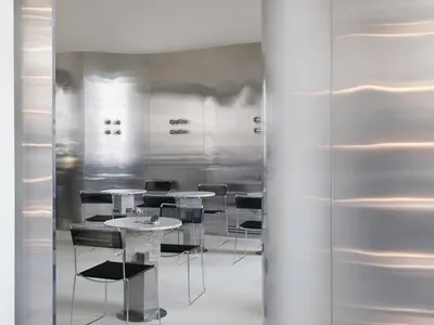 Minimalist restaurant interior with silver steel walls and tables and chairs.