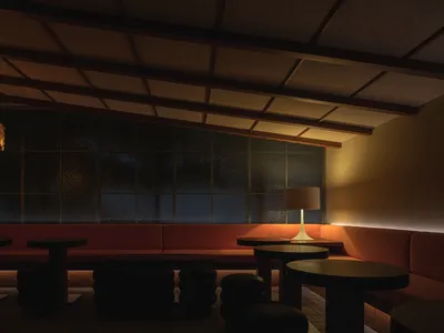A cozy cafe interior with fabric seating, a concrete column, wooden lampshades, and a warm ambiance.