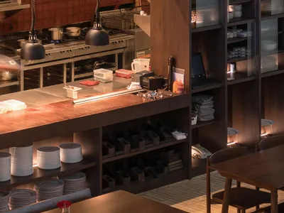 Industrial-style restaurant interior featuring wooden tables and metal shelving.