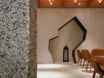 Modern restaurant interior with concrete walls and floor, geometric wall feature