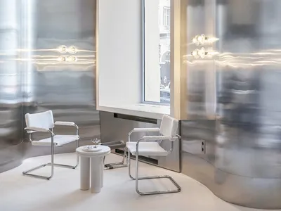 A modern restaurant with metallic walls and white furniture and table.