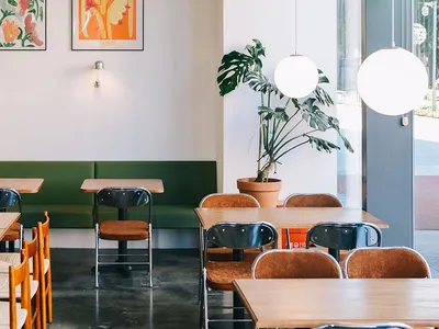Cafe interior with wooden tables, concrete flooring, and potted plants.