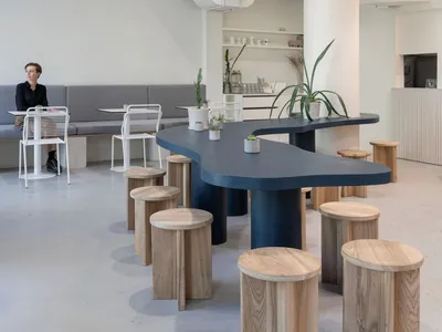 Interior view of a modern restaurant featuring minimalist design with concrete, wood, and metal elements.