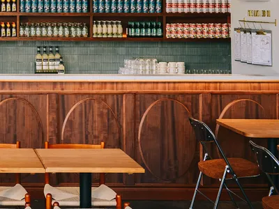 An image showcasing a cafe interior with wooden shelving filled with canned drinks and bottles arranged in an elegant display