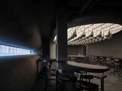 Industrial-style restaurant interior featuring metal stools and concrete walls and floor
