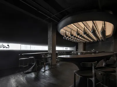 An industrial-themed restaurant interior with a metal counter and hanging lamps.