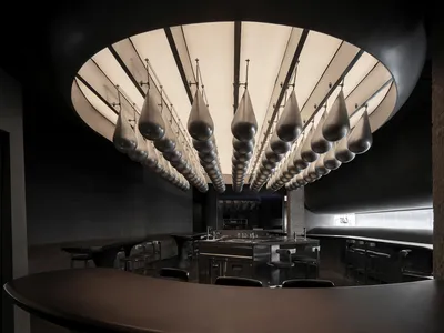 A modern restaurant bar with a curved countertop and hanging silicone drop lights.