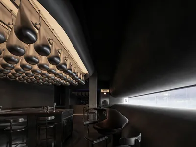 Minimalist design featuring modern restaurant interior with hanging silver light fixtures in a black space.